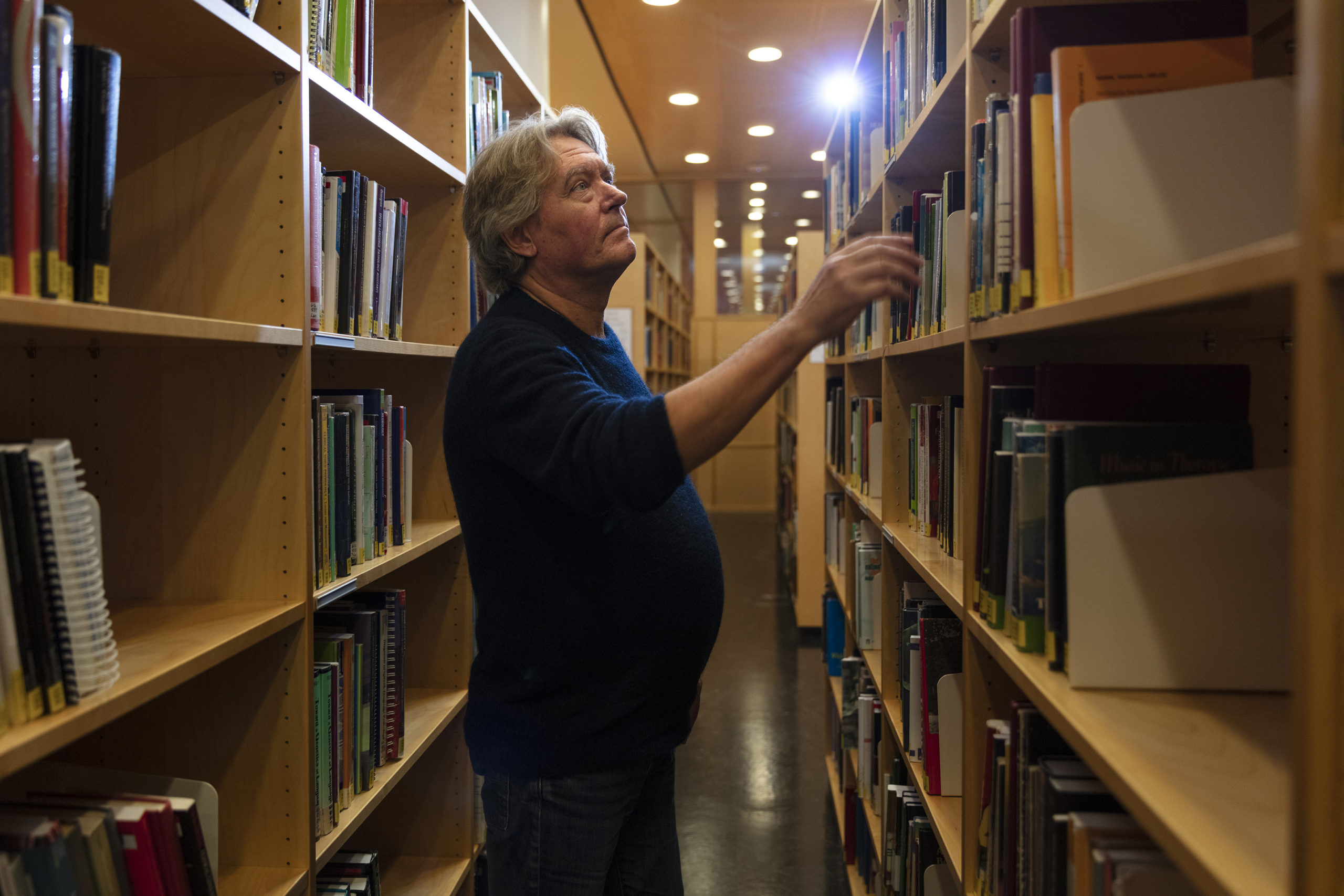 Mann i et bibliotek som leter etter en bok.