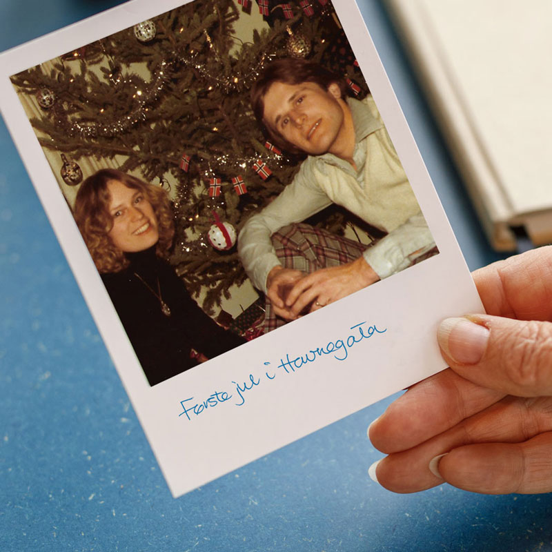 Eldre polaroidbilde av blide av 2 mennesker foran et juletre
