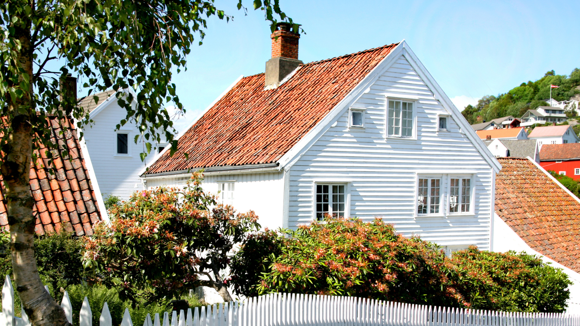 Pent, hvitt hus på en fin sommerdag.